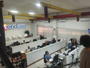 Oficina amplia del periódico El Meridiano, con varias personas trabajando en escritorios con computadoras. En la pared se ve el logo ‘Meridiano Grupo de Comunicaciones’. El ambiente refleja una redacción activa y colaborativa.